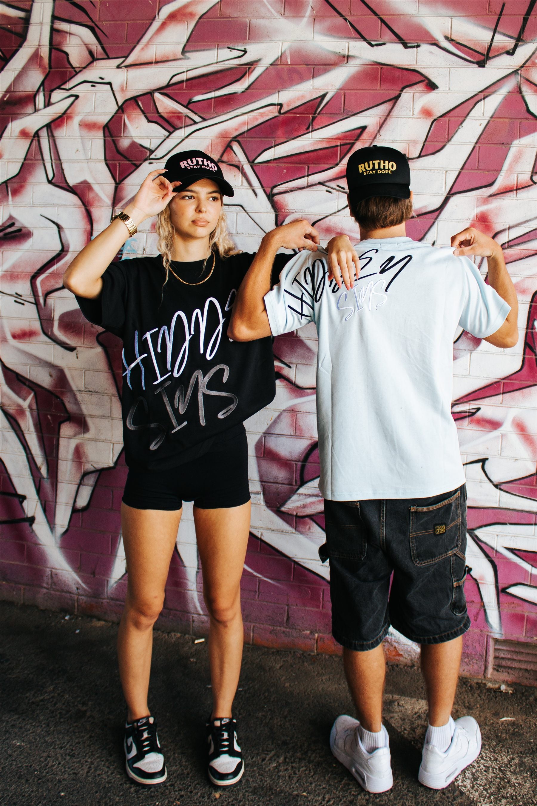 Hidden Sins streetwear worn in front of graffiti wall